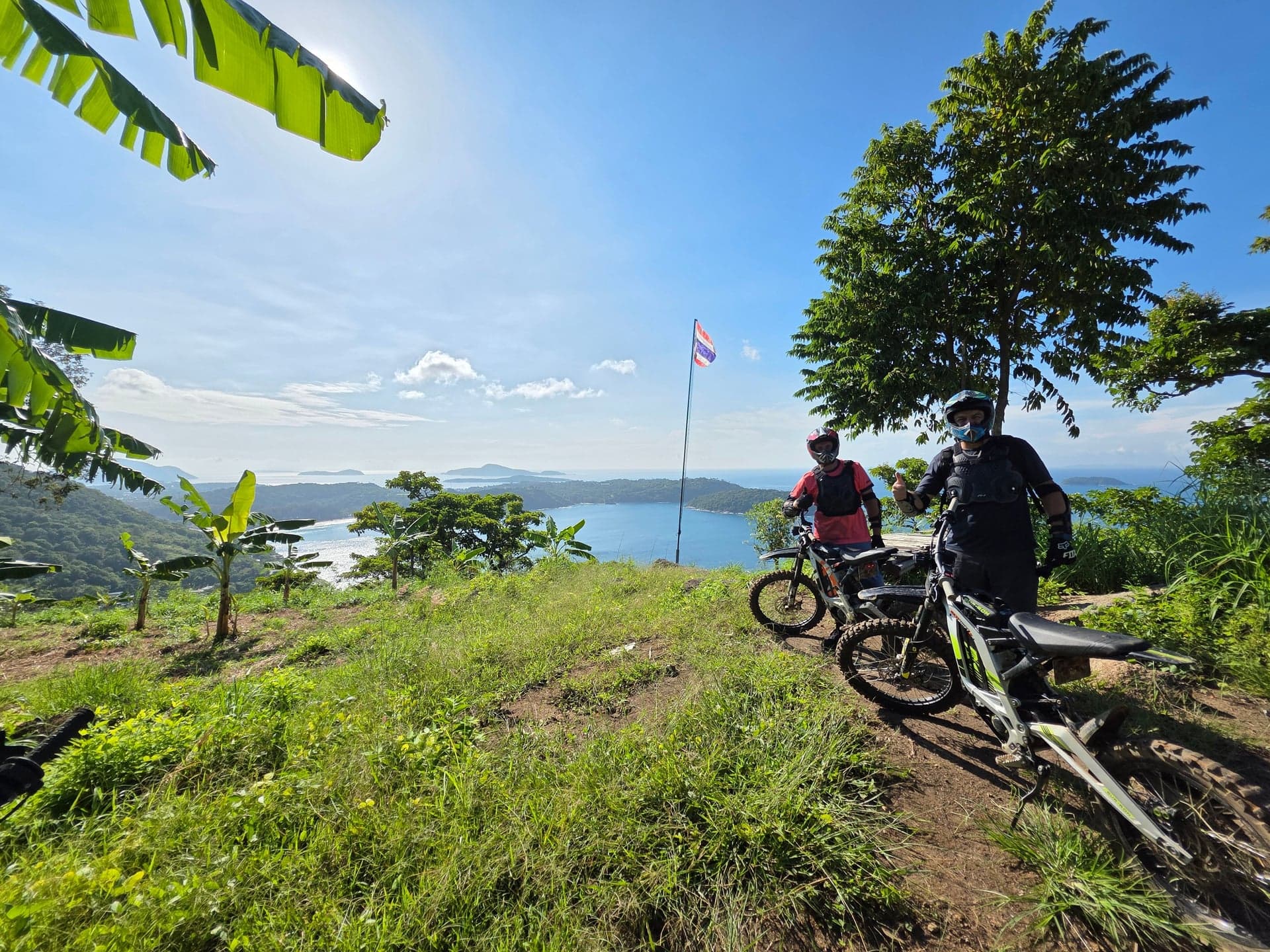 Two people on electric motorbikes at Laem Krating Viewpoint, Phuket, Thailand.